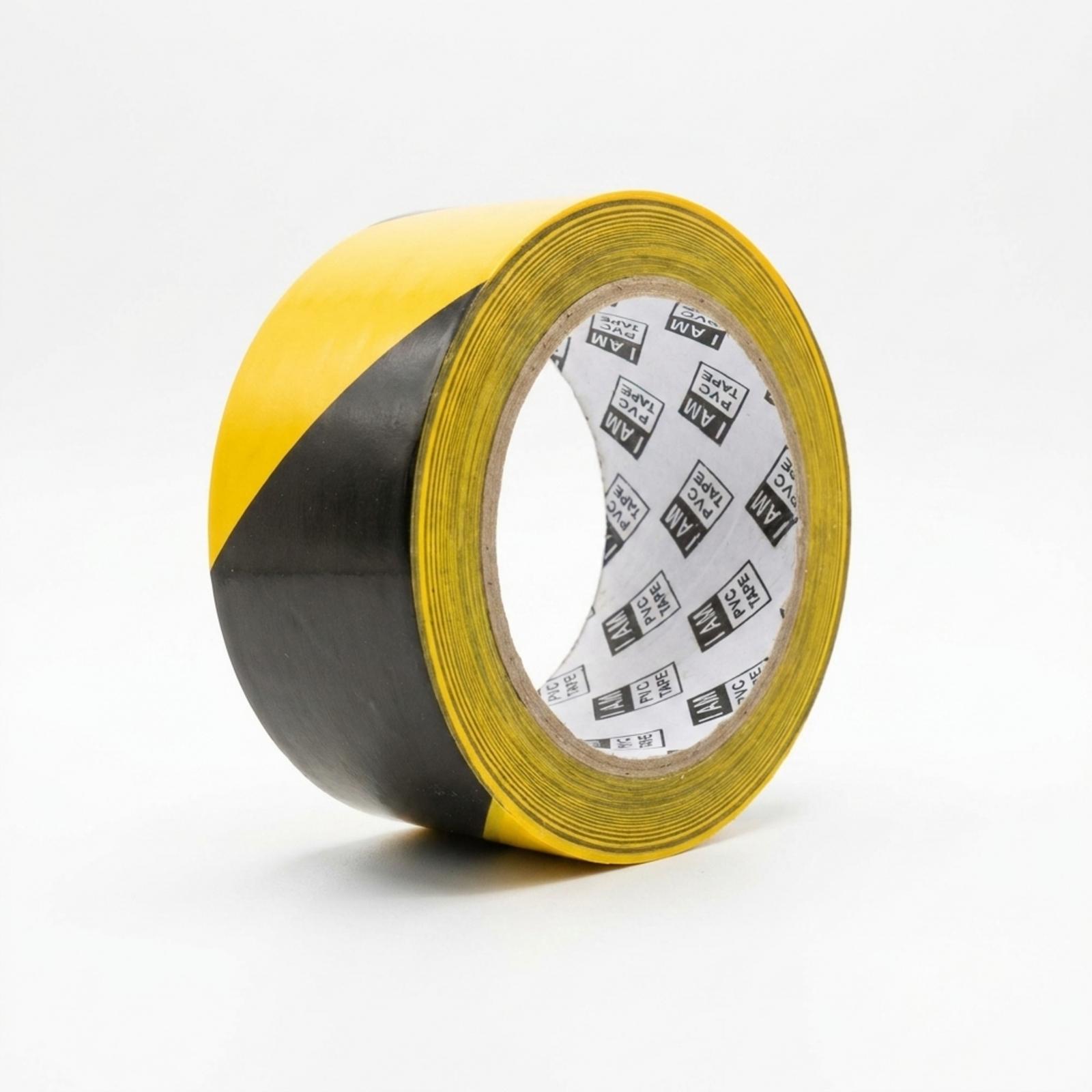 A roll of hazard tape standing at an angle, its diagonal black and yellow stripes running across the face and the I AM PVC Tape core liner visible.